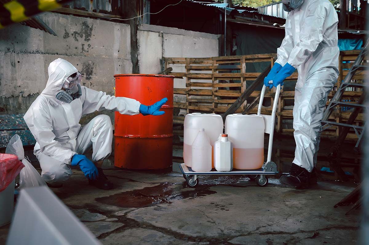 Technicians in PPE sealing biohazard containers